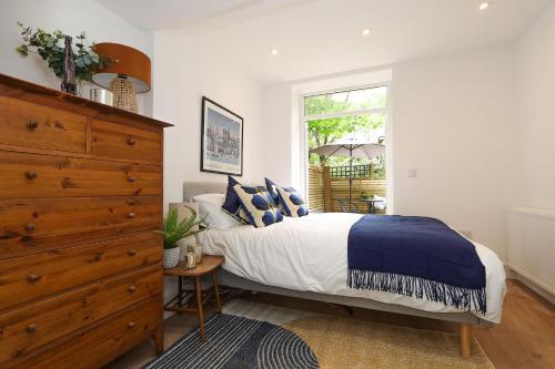 a bedroom with a bed and a dresser and a window at The London Secret, 1 bed flat with patio - Zone 2 in London