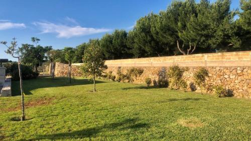 a stone wall with trees in a field at Villetta La Lama in Torre Lapillo