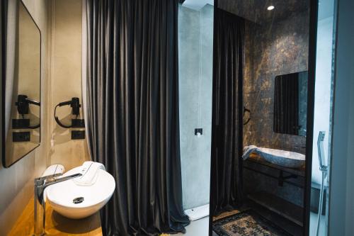 a bathroom with a black shower curtain and a sink at Dot Tradition in Vlorë