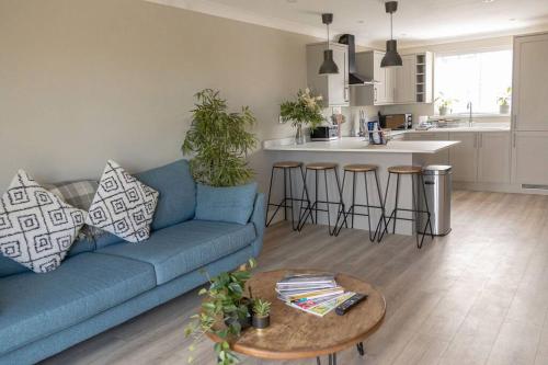 a living room with a blue couch and a table at The Rosewood, Cornwall. in Roche