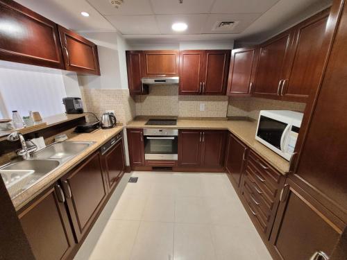 a small kitchen with wooden cabinets and appliances at Marina Deluxe 2, family only in King Abdullah Economic City