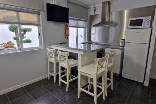 a kitchen with a counter with stools and a refrigerator at Casa de Férias_As Oliveiras I in Espinho