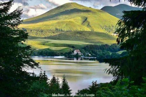 a house on a lake in front of a mountain at Appartement Dans un village en Auvergne sancy in Égliseneuve-dʼEntraigues