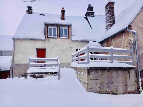 a house covered in snow with a white fence at Appartement Dans un village en Auvergne sancy in Égliseneuve-dʼEntraigues