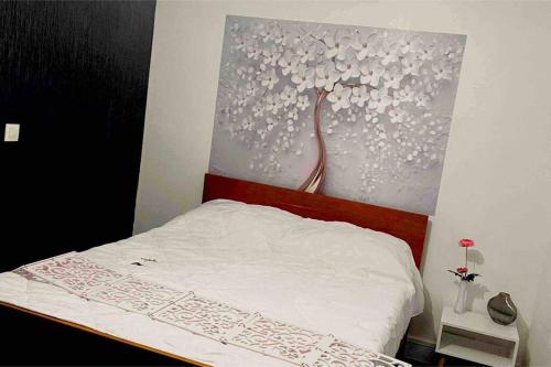 1 cama en un dormitorio con una pintura en la pared en Appartement Dans un village en Auvergne sancy, en Égliseneuve-dʼEntraigues