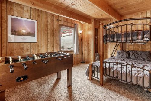 Un dormitorio con una litera y una gran sala de juegos. en Forest Edge Retreat - Cozy, log cabin with a wood burning fireplace! Pool Table, Foosball and Darts!, en Big Bear City
