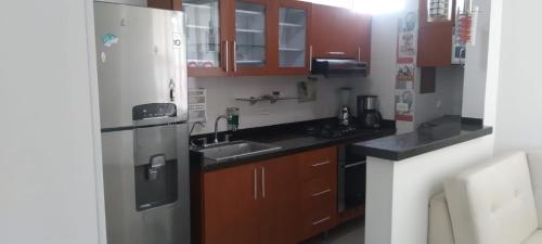 a kitchen with wooden cabinets and a stainless steel refrigerator at Perfecto Apartamento en el Mejor Sector in Cúcuta