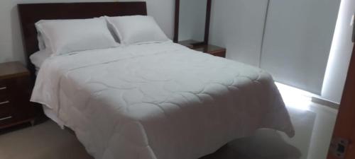 a bed with white sheets and pillows in a room at Perfecto Apartamento en el Mejor Sector in Cúcuta