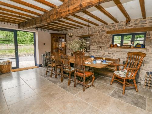 a dining room with a stone wall and a wooden table and chairs at Ty Sinsir in Crickhowell