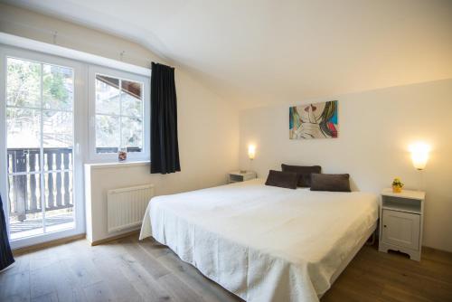 a bedroom with a large white bed and a window at Alpenhof by AlpenTravel in Bad Gastein
