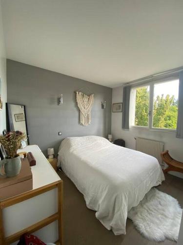 a bedroom with a white bed and a window at Bel appartement cosy proche de Paris in Saint-Maur-des-Fossés