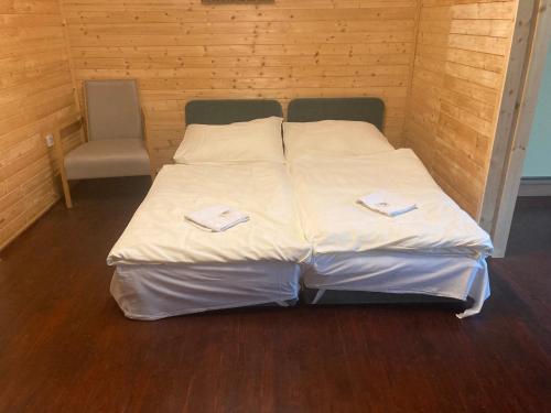 uma cama com lençóis brancos e uma cadeira num quarto em Chata Eva Jundrov em Komín