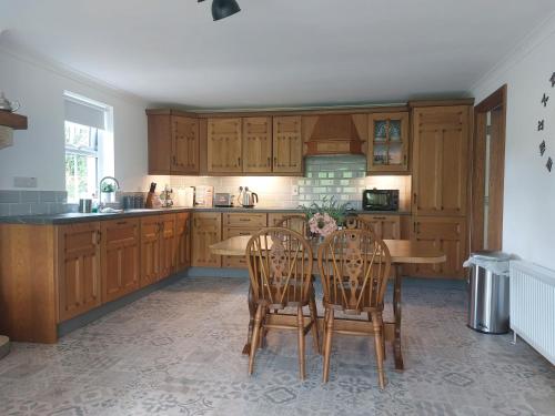 a kitchen with wooden cabinets and a table and chairs at The Cove in Aughnacloy