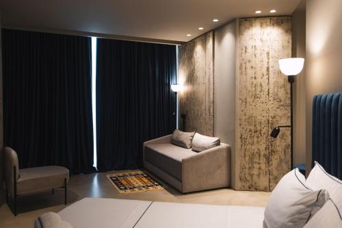 a bedroom with a couch and a chair and a window at Dot Tradition in Vlorë