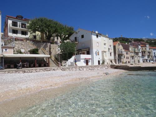 un gruppo di edifici su una spiaggia vicino all'acqua di Apartments Authentic Baska 1 a Baška