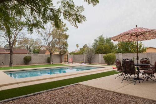 a table and chairs with an umbrella next to a swimming pool at Cozy Quiet two story home pool outdoor entertaining bbq in Chandler