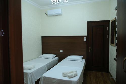 two beds in a room with white sheets and towels at HOTEL MEHRIBON in Samarkand