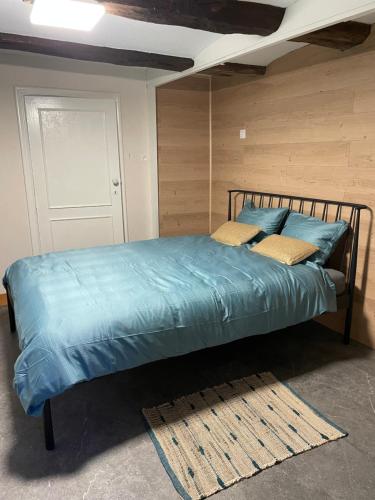 Bett mit blauer Bettwäsche und Kissen in einem Zimmer in der Unterkunft Casawellness améthyste ou jaspe océan avec jacuzzi intérieur in Floreffe