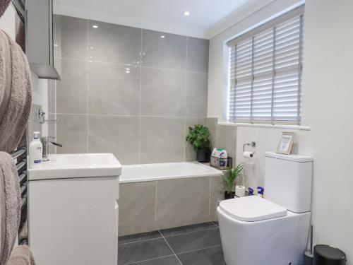a bathroom with a tub and a toilet and a sink at Closefield in Leighton Buzzard