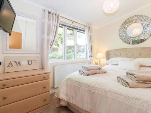 a bedroom with a bed and a dresser and a window at Nutkins Lodge in Windermere