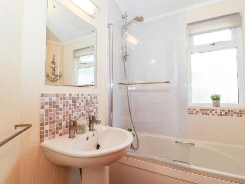 uma casa de banho branca com um lavatório e um chuveiro em Nutkins Lodge em Windermere