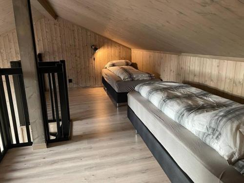two beds in a room with wooden walls at Skaidi Logde- near salomon river and golf course in Hammerfest