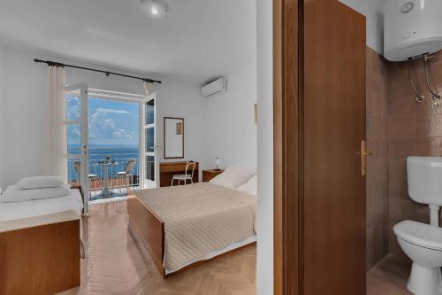 a bedroom with a bed and a bathroom with a balcony at Beachfront Rooms Ana in Tučepi