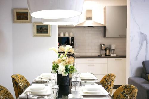 una mesa de comedor con platos blancos y flores en New & Luxury apartment Tony en Split