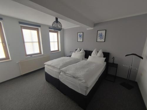 una camera da letto con letto, lenzuola e cuscini bianchi di Haus Blumenampel a Smalcalda