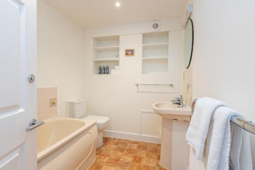 a bathroom with a tub and a toilet and a sink at The Granary in Beaminster