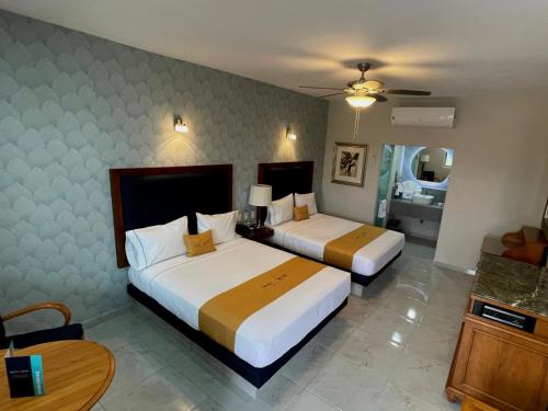 Cette chambre comprend 2 lits et une table. dans l'établissement Hotel Maioris Bellavista, à Culiacán