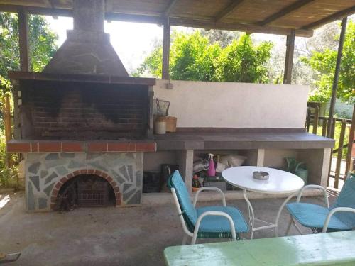 a patio with a fireplace with chairs and a table at Zephyr Guest House in Lefokastro