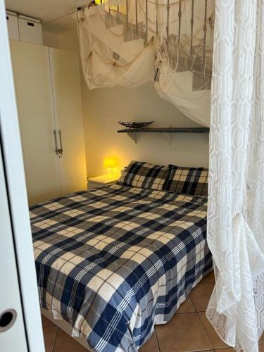 a bedroom with a bed with a blue and white checked blanket at Albamare apartment in Marettimo
