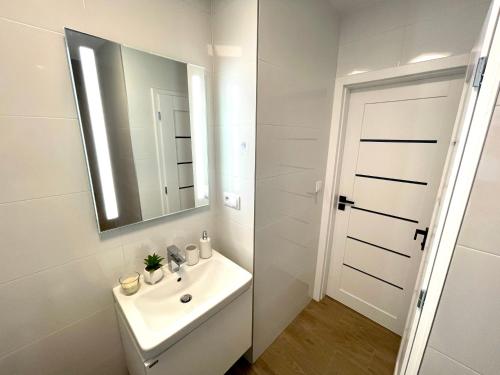 a white bathroom with a sink and a mirror at Mand apartmán in Žilina