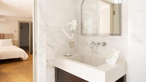 ein weißes Badezimmer mit einem Waschbecken und einem Spiegel in der Unterkunft Ishak Pasa Palace by Signature Hotels in Istanbul