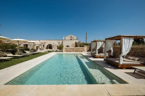 a swimming pool with chairs and a house at Agriturismo Masseria Costarella in Borgagne