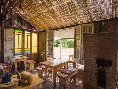 a room with wooden tables and a brick fireplace at Caliu Earthship Ecolodge in Colonia del Sacramento