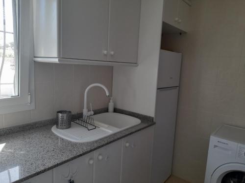 uma cozinha branca com um lavatório e uma máquina de lavar louça em Villa Adriana v rezidencii Toscamar em Xàbia