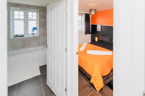 Rugby Modern 3 Bed 6 guest house في Clifton upon Dunsmore: غرفة نوم بسرير وحوض استحمام وسرير