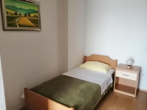 een kleine slaapkamer met een bed en een foto aan de muur bij Apartmani Grgo in Živogošće