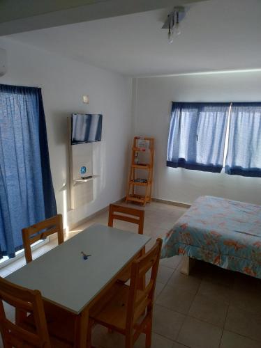 Cette chambre comprend une table, un lit et des rideaux bleus. dans l'établissement Vistas de la meseta Patagónica, à Trelew