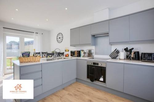 a kitchen with white cabinets and a large window at Harvey's Yard Luxury Home-St Ives-Beach-Parking 5* in Hayle