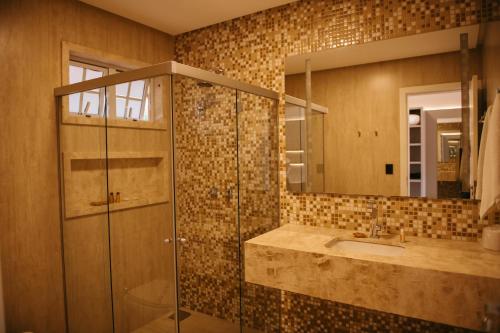 a bathroom with a shower and a sink and a mirror at Engenho da Serra Hotel EcoResort in Capitólio