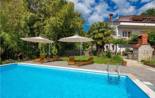 a swimming pool with two umbrellas and a house at Beautiful Apartment In Ika With Wifi in Ika