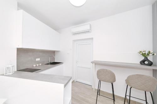 a white kitchen with two stools at a counter at Silver stars 1 in Zadar