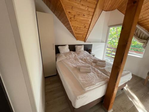 Cama grande en habitación con techo de madera en VÁRLAK VENDÉGHÁZ, en Siófok