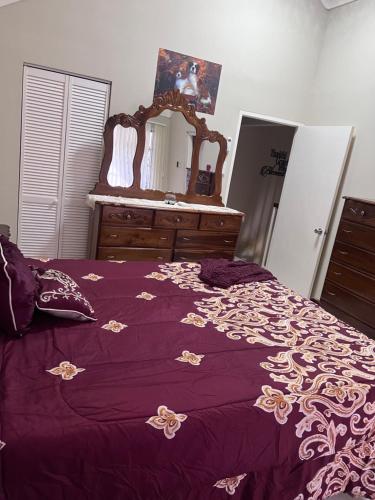 a bedroom with a purple bed with a dresser and a mirror at Comfort Rest in Ocho Rios