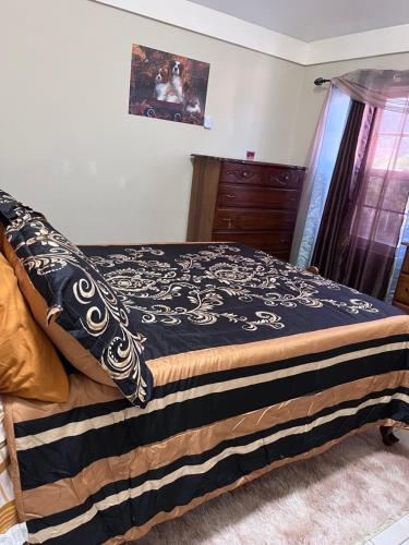 um quarto com uma cama com um cobertor preto e castanho em Comfort Rest em Ocho Rios