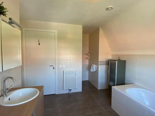 een badkamer met een wastafel, een bad en een koelkast bij Het Pauzeerhuis in Middelburg
