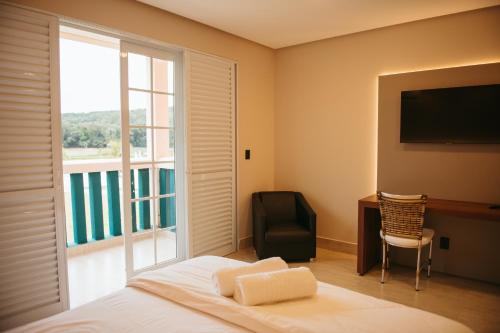 a bedroom with a bed and a window and a television at Engenho da Serra Hotel EcoResort in Capitólio